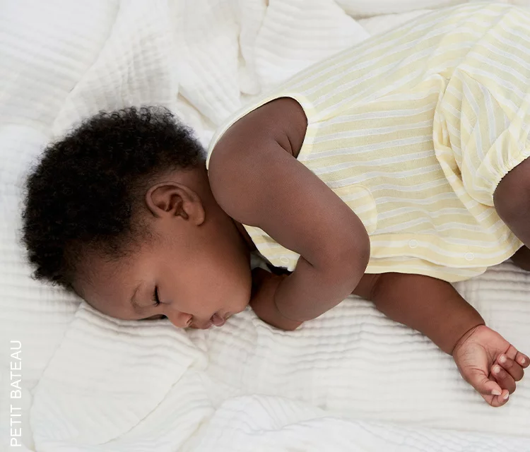 baby girl asleep on her side, wearing a cute romper and day napping