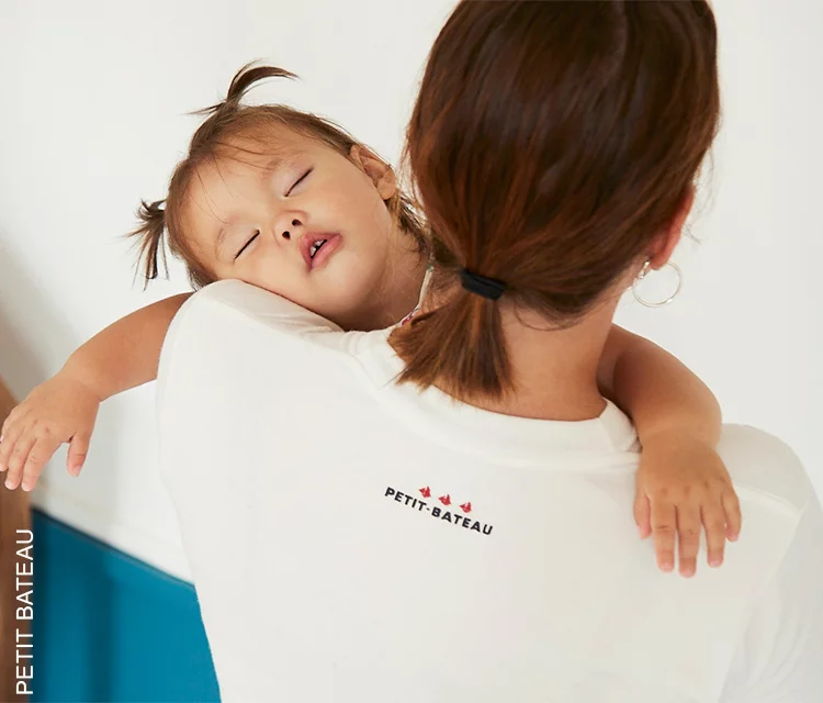 baby girl fallen asleep on her mum's shoulder. mother carrying the girl to go to sleep